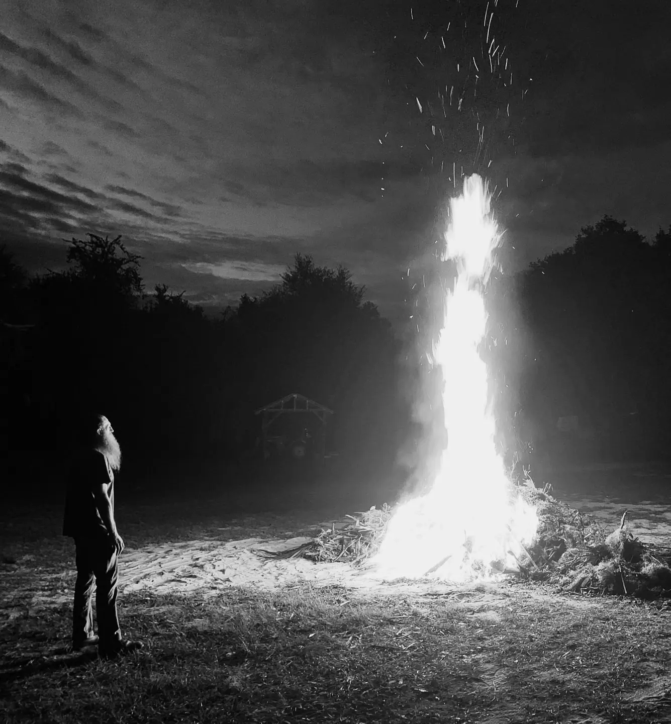 Jonathan Harrington standing beside a large fire at night